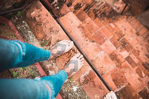 在一栋旧建筑的陡峭楼梯上纹身的女性脚 在一栋旧建筑的陡峭楼梯上纹身的女性脚