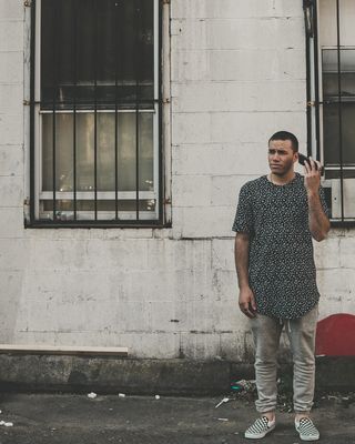 白天，一名男子手持电话站在大楼前