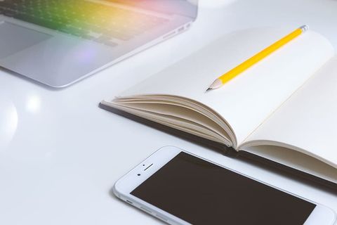 办公室白色办公桌，带笔记、智能手机和笔记本电脑