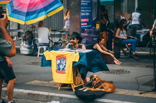 狗躺在人行道上，旁边坐着人