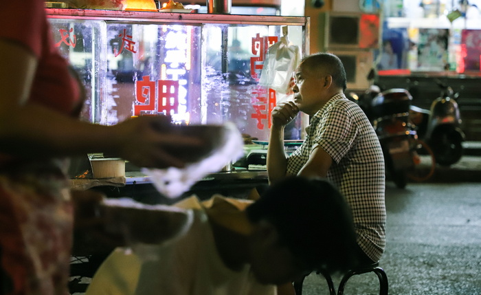一个男人坐在桌子旁边，手放在下巴上