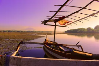 日落时，白色和棕色划艇在平静的水面上划行