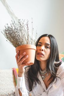 女人把盆栽放在脸旁的照片