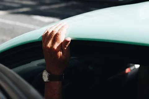 戴着圆形白色模拟手表的人，黑色表带固定在车顶上