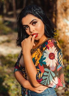 一位身穿花卉上衣的女士咬拇指时摆出姿势的照片