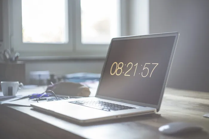 窗口附近桌子上有苹果魔术鼠标的MacBook