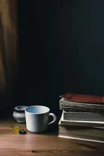 书籍旁的白色陶瓷杯和一次性打火机 书籍旁的白色陶瓷杯和一次性打火机