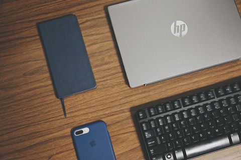 棕色表面上的灰色HP笔记本电脑、智能手机和键盘 棕色表面上的灰色HP笔记本电脑、智能手机和键盘