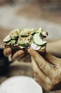 拿着绿色蔬菜咬过的面包的人