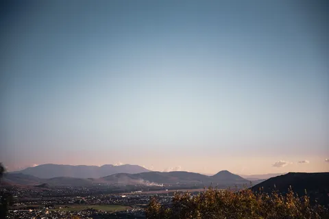 日落时群山环抱的绿色村庄上空的柔和天空 日落时群山环抱的绿色村庄上空的柔和天空