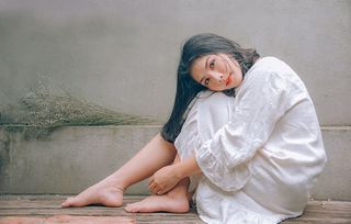 穿着白色连衣裙的女子坐在木地板上