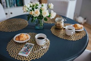 带白色花朵和金色咖啡垫的圆形早餐桌