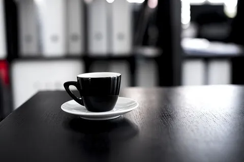 黑木桌上的黑白陶瓷茶杯和茶托 黑木桌上的黑白陶瓷茶杯和茶托