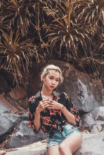 坐在线状叶子植物附近的女人 坐在线状叶子植物附近的女人