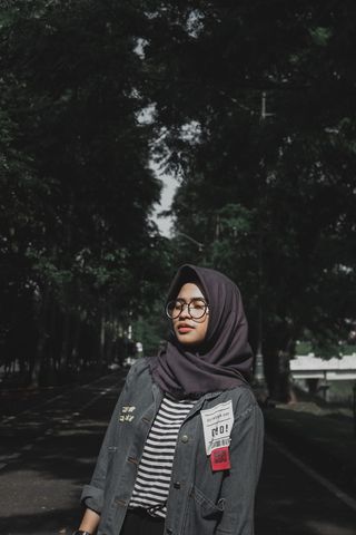 女孩站在绿树成荫的街道中间