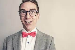 身穿灰色西装夹克的男子微笑的照片