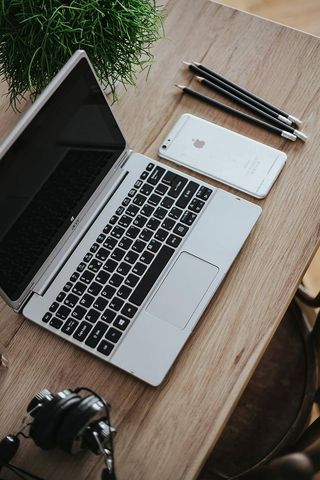 银色宏碁笔记本电脑放在一张木桌子上，上面有一株绿色植物、铅笔和一部苹果iPhone