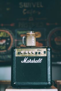 黑色 Marshall 吉他放大器，顶部有玻璃杯，装满饮料