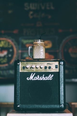 黑色 Marshall 吉他放大器，顶部有玻璃杯，装满饮料