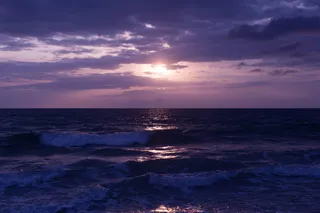 日落时蓝色海洋和乌云的照片