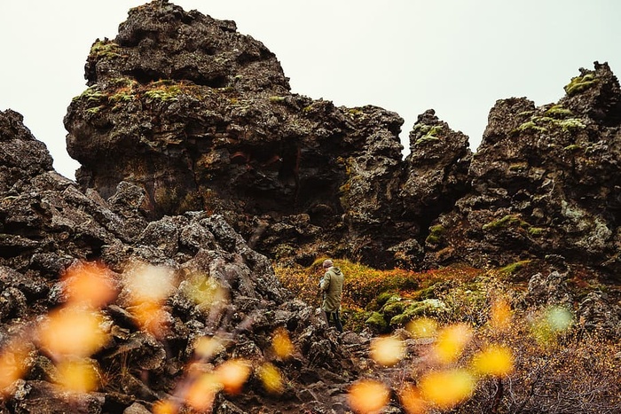 一位摄影师在布满青草的火山岩山丘上拍照