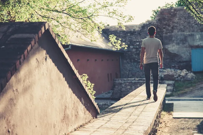 身穿灰色T恤和黑色牛仔牛仔裤的男子走向灰色混凝土通道