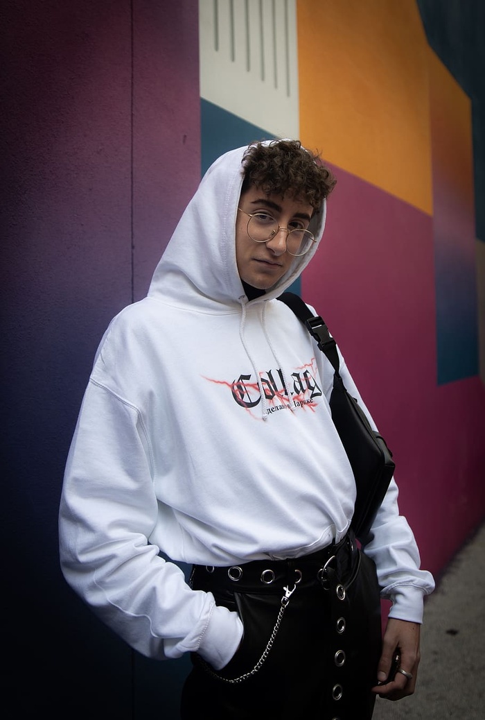 身穿白色连帽衫的男子站在五颜六色的墙上