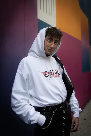 身穿白色连帽衫的男子站在五颜六色的墙上