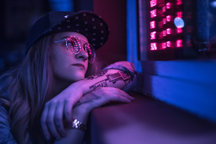 戴黑帽子的女人看着紫色的LED灯