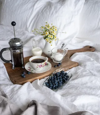 在咖啡机和咖啡杯之间放一杯咖啡，在棕色托盘上放一杯糖和牛奶