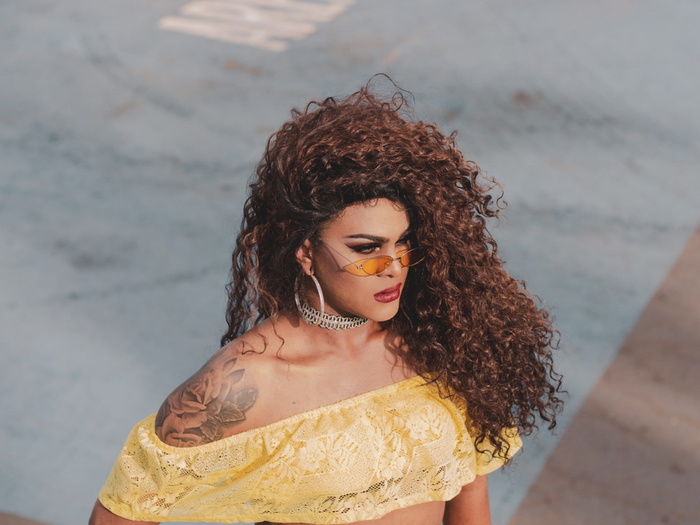 身穿黄色短上衣和太阳镜的女子站在那里的照片