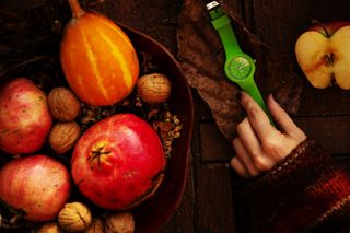 在苹果片和果篮之间触摸绿色模拟手表的人