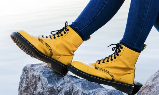 在灰色岩石上穿着黄色Doc Martens Airway靴子的人