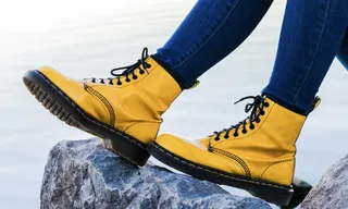 在灰色岩石上穿着黄色Doc Martens Airway靴子的人