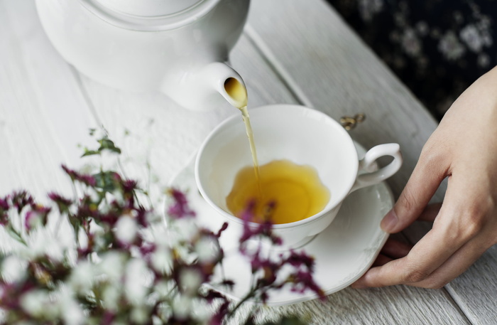 在茶杯上倒茶的人