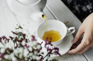 在茶杯上倒茶的人