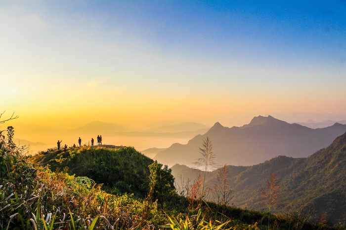 黄金时代，人们站在山顶靠近面向群山的草地上的照片
