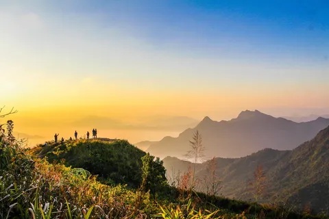 黄金时代,人们站在山顶靠近面向群山的草地上的照片 黄金时代,人们站在山顶靠近面向群山的草地上的照片