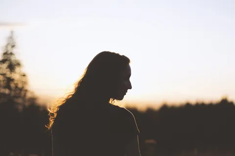 日落时女人和树的剪影