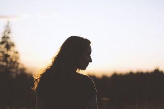 日落时女人和树的剪影