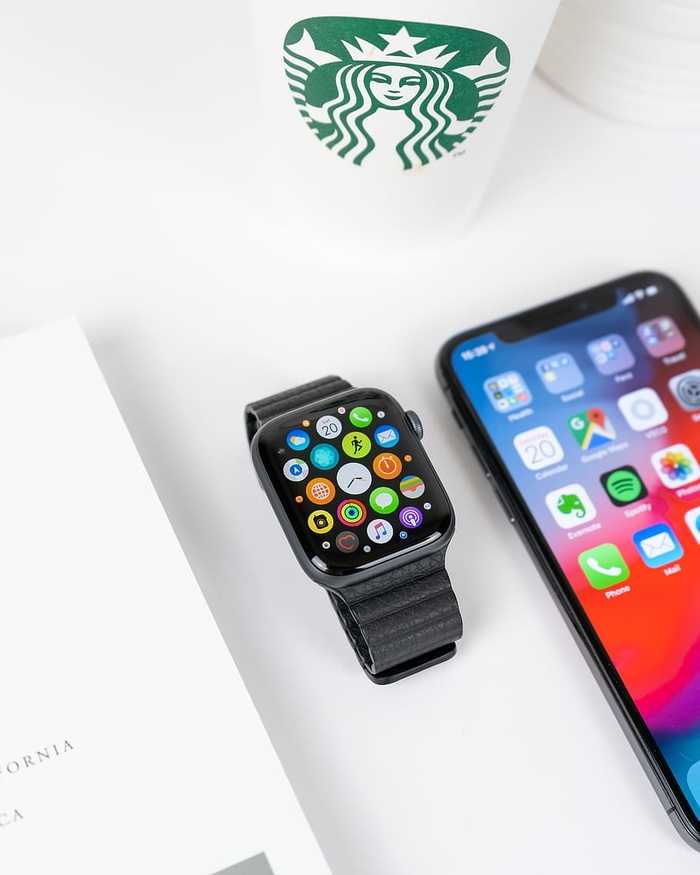 黑色铝制表壳苹果手表，在太空灰色iPhone X旁边有黑色运动表带