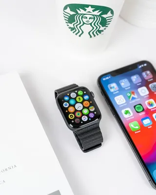 黑色铝制表壳苹果手表，在太空灰色iPhone X旁边有黑色运动表带