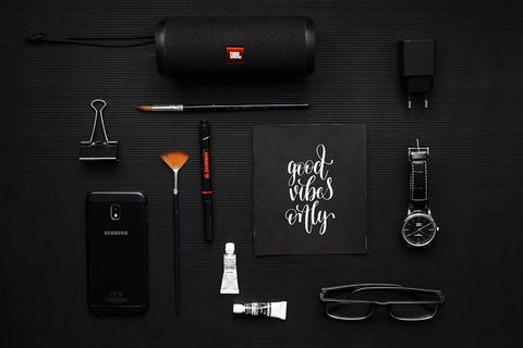 黑色织物上的活页夹、扬声器和眼镜旁的智能手机特写照片