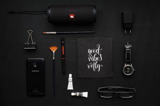 黑色织物上的活页夹、扬声器和眼镜旁的智能手机特写照片