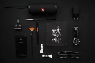 黑色织物上的活页夹、扬声器和眼镜旁的智能手机特写照片