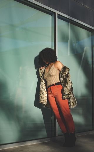 穿着背心和裤子靠在墙上的女人