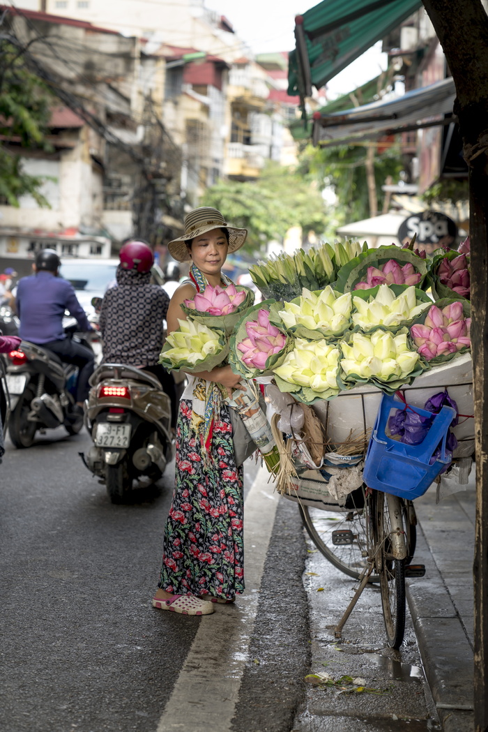 在道路和建筑物附近站立并携带鲜花的妇女