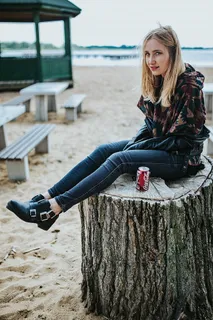 美丽的金发女人在海滩边的树桩上拿着一罐可乐放松 美丽的金发女人在海滩边的树桩上拿着一罐可乐放松