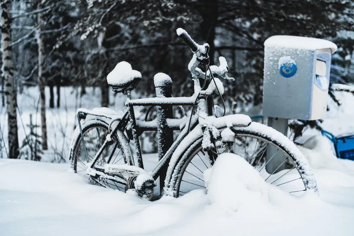 黑色通勤自行车停在雪地上的邮箱旁