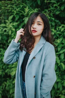 穿着灰色外套的女人站在绿色植物旁边 穿着灰色外套的女人站在绿色植物旁边